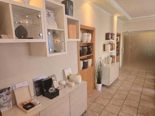 Innenansicht eines Geschäfts mit hellen Regalen, die Vasen, Schmuck und dekorative Objekte ausstellen.