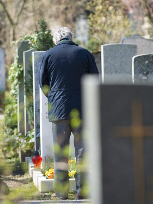 Ein Mann, trauernd vor einem Grab